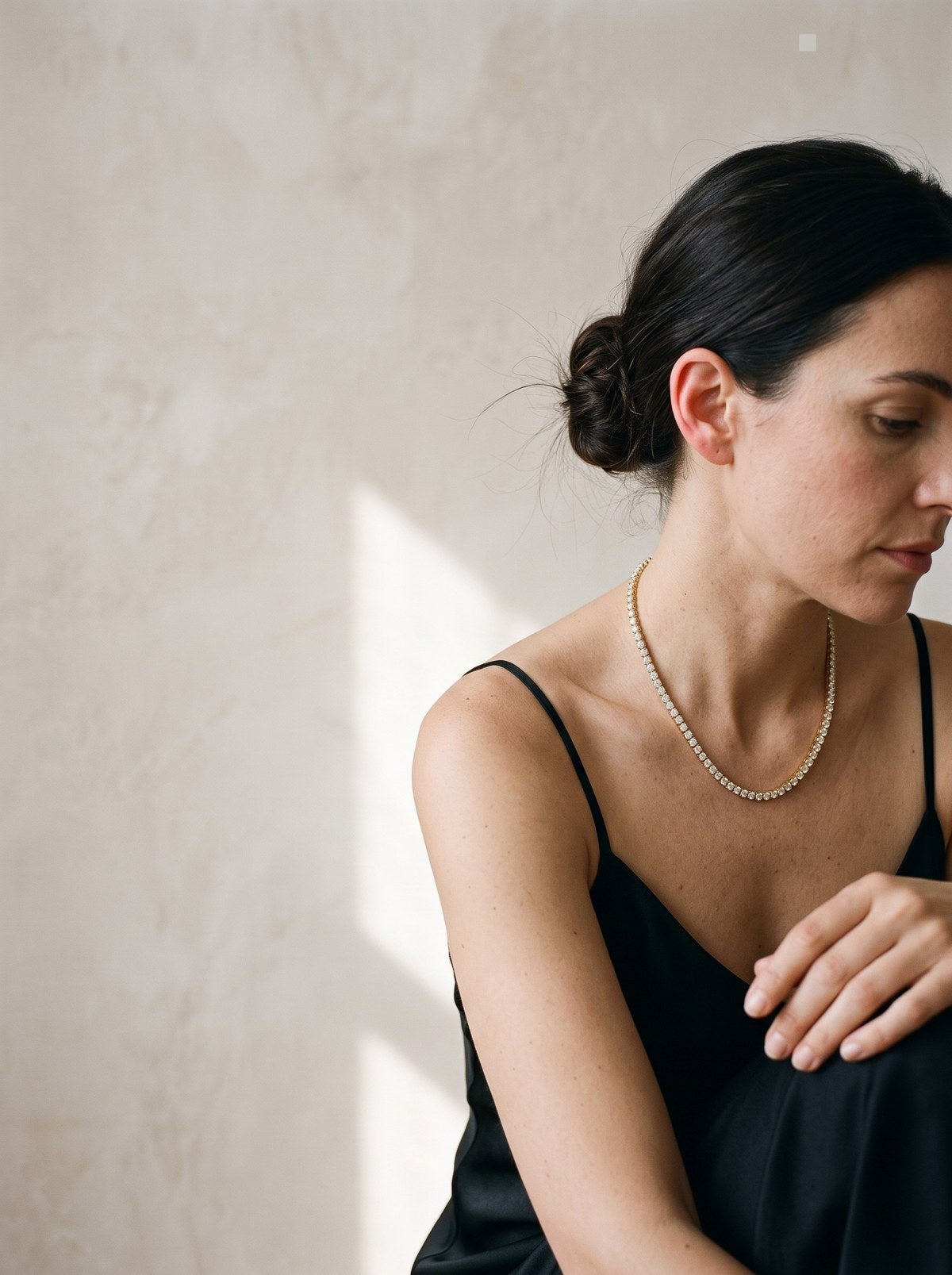 A wrist resting on a table, wearing a gold tennis bracelet