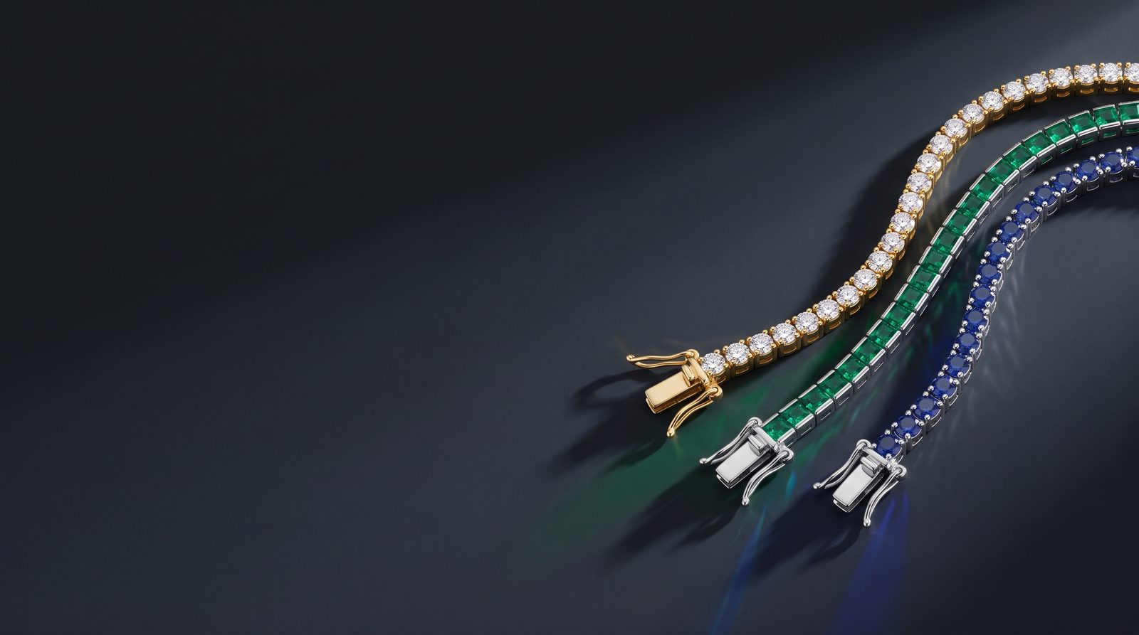 Three tennis bracelets laid side by side, in gold, in silver and in color
