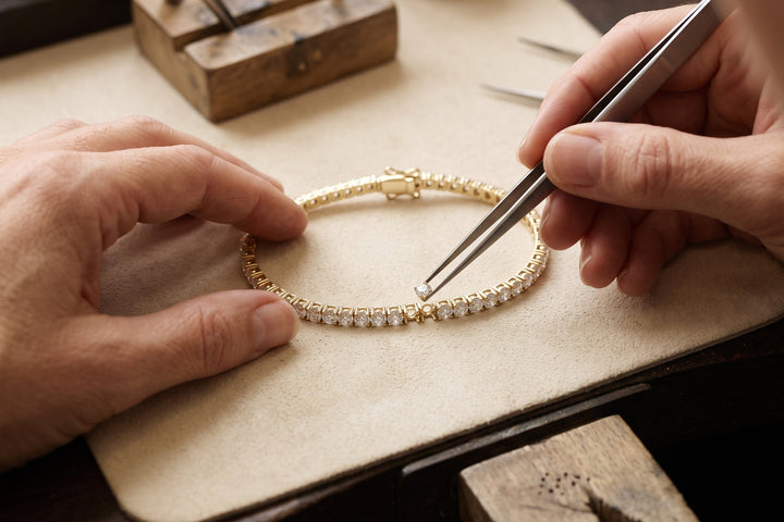 A jeweller setting one stone into a gold tennis bracelet by hand